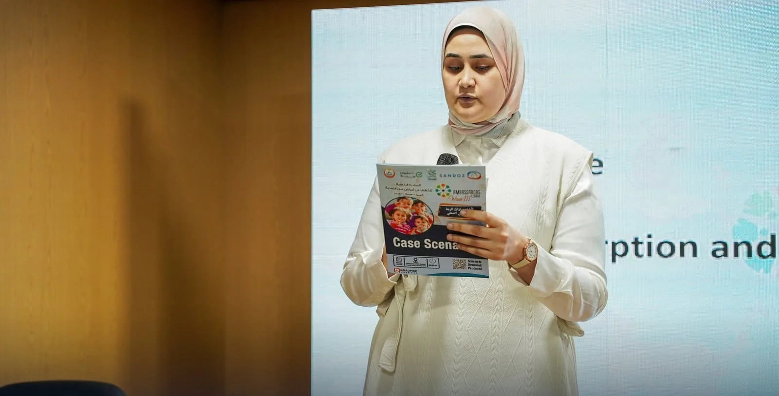 Ambassadors League workshop — physician reading the case scenario booklet on stage