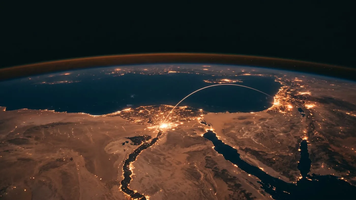 Egypt and the surrounding region at night from orbit — the Nile, its delta and Cairo lit in gold, a luminous arc linking the capital outward across MENA